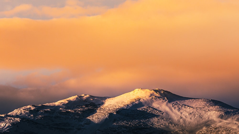 snow covered mountain under orange sky