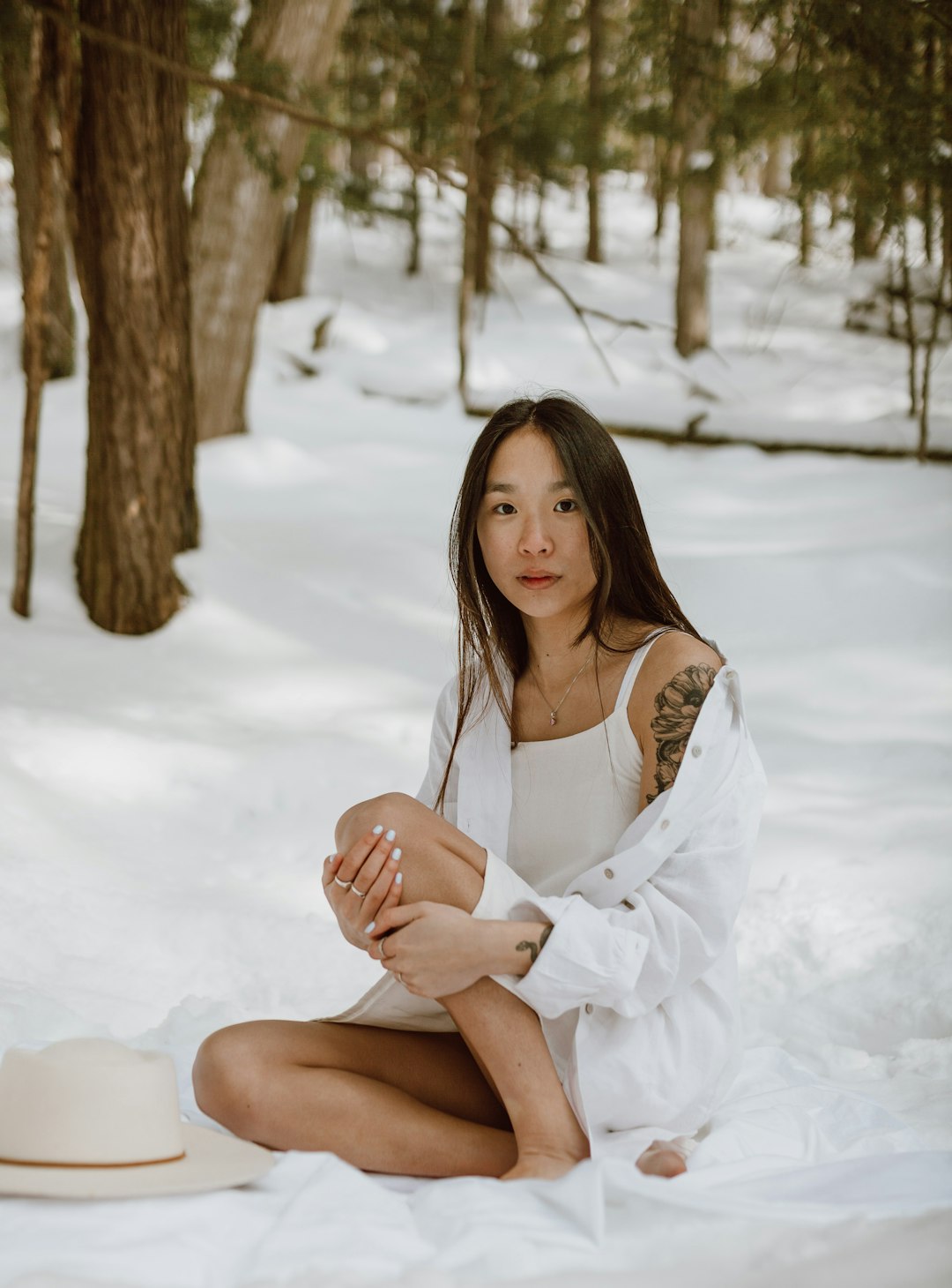 woman in white long sleeve shirt sitting on snow covered ground during daytime
