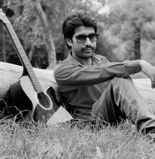 Casual scene of a person wearing a black t-shirt with a samba quote, sitting relaxed with a guitar nearby.