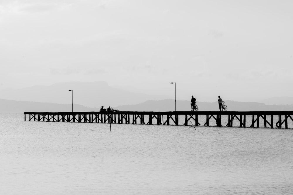grayscale photo of people walking on bridge