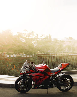 A sleek red sports bike parked outside Varsha Velocity showroom in Mysore under bright sunlight