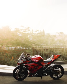 A sleek motorcycle parked beside a shiny red sports car under a clear blue sky.