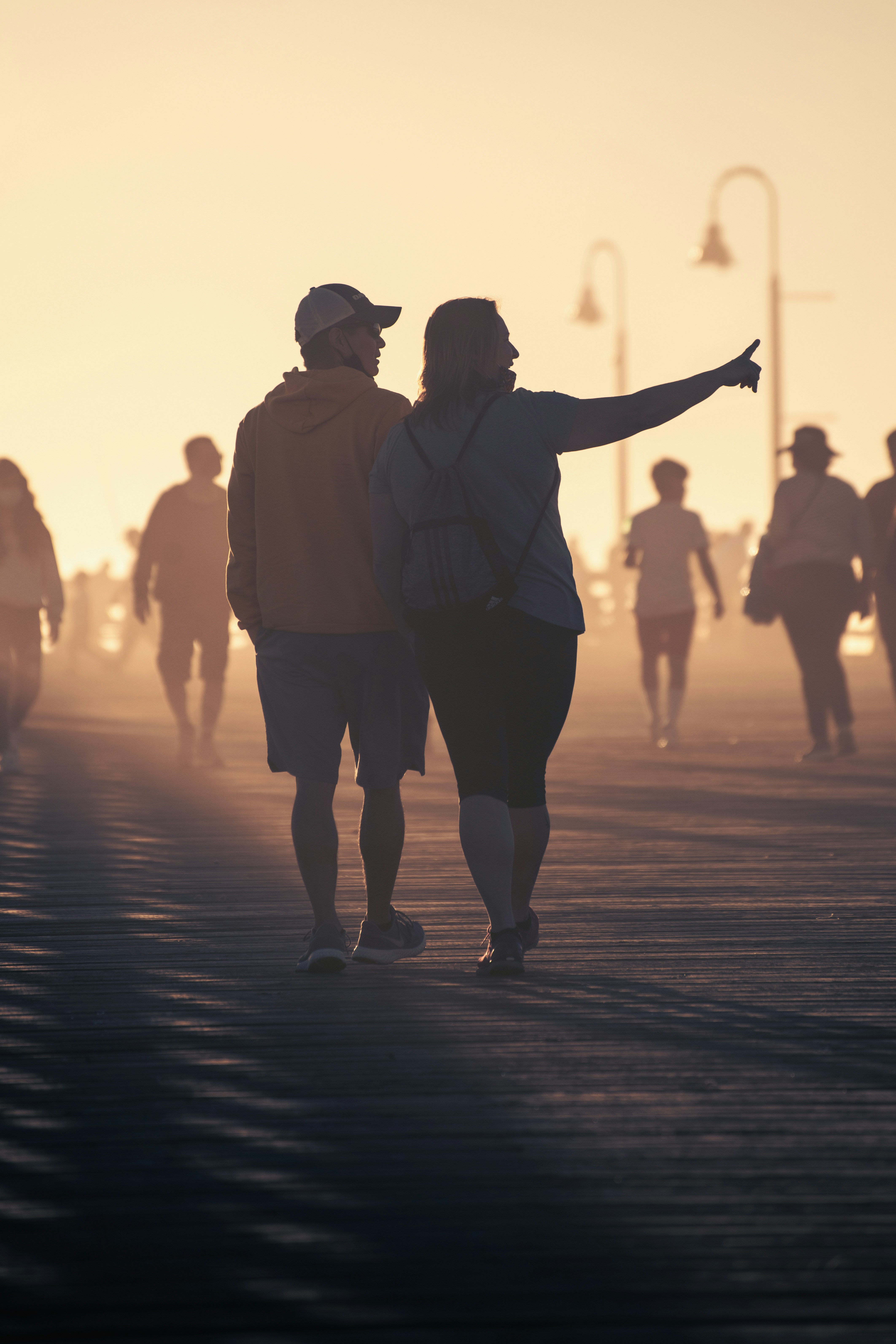 man in white dress shirt and black shorts walking on the street during sunset