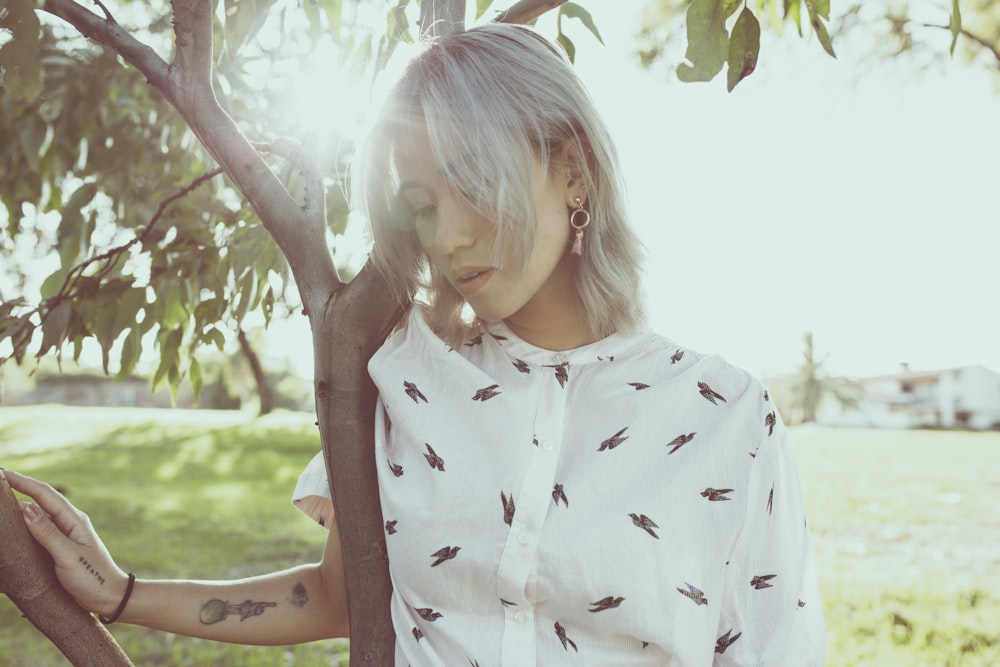 girl in white and black star print dress shirt standing under green tree during daytime