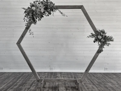 An elegant floral arch with soft ivory and blush artificial flowers set against a black and gold backdrop.