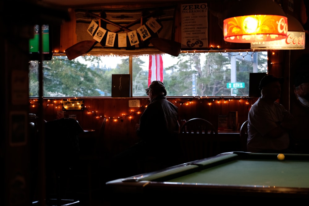 man in black jacket standing near pool table