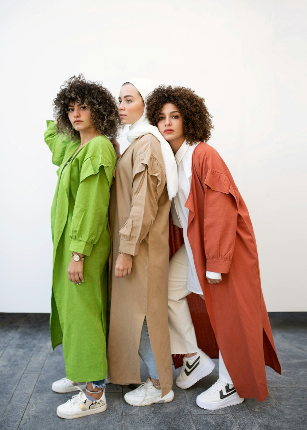 2 women in white and brown coat standing on gray concrete floor