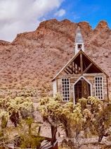 white wooden house near brown mountain under blue sky during daytime