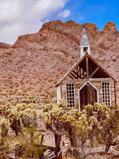 white wooden house near brown mountain under blue sky during daytime