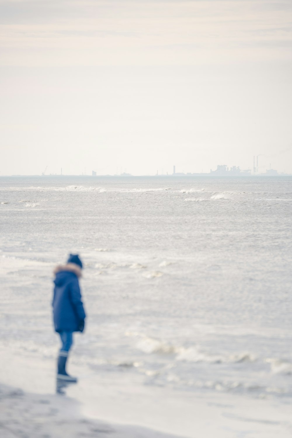 person in blue jacket walking on snow covered field during daytime