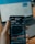 a person holding a cell phone in front of a laptop
