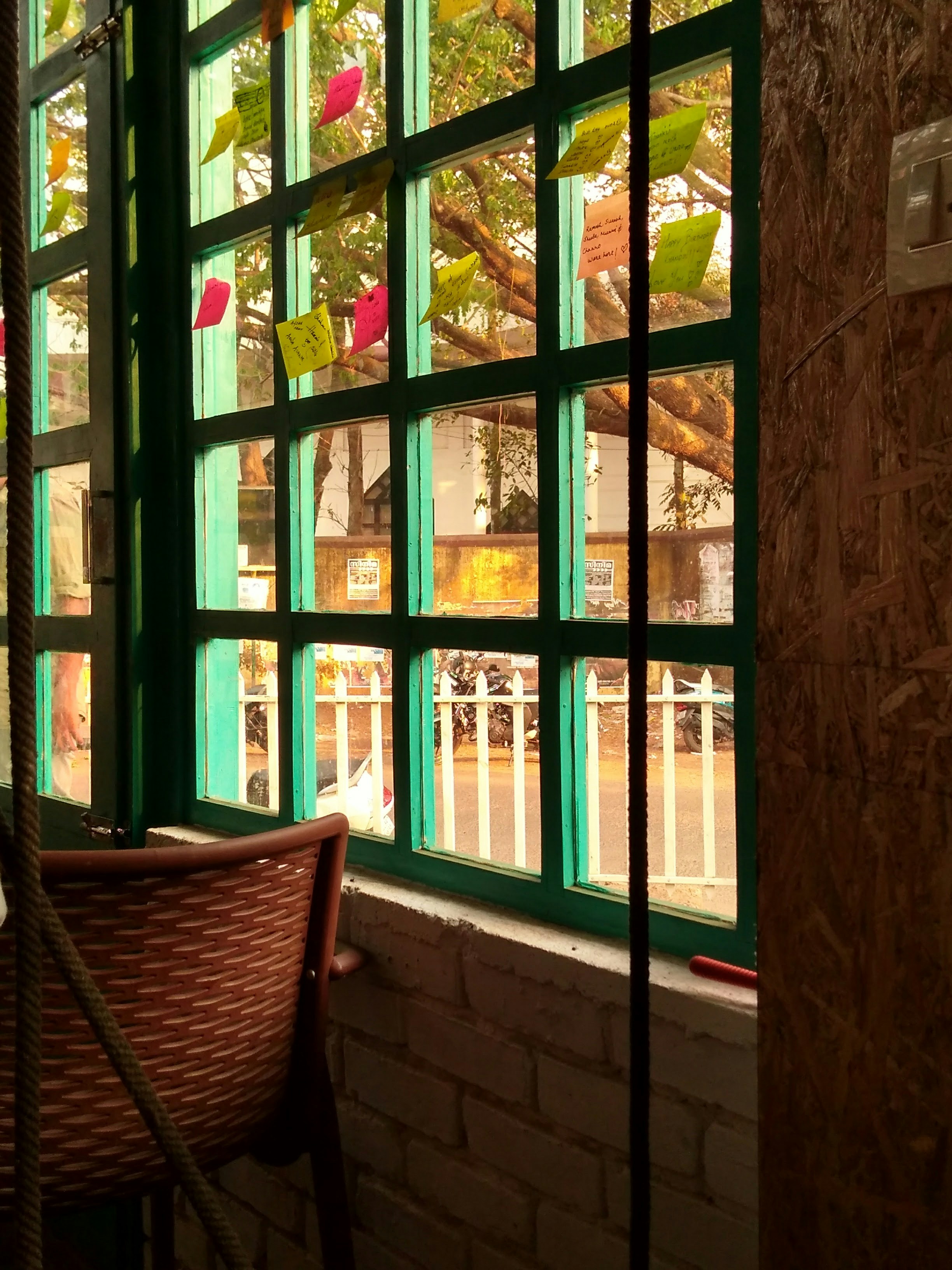 brown wicker armchair near green wooden framed glass window
