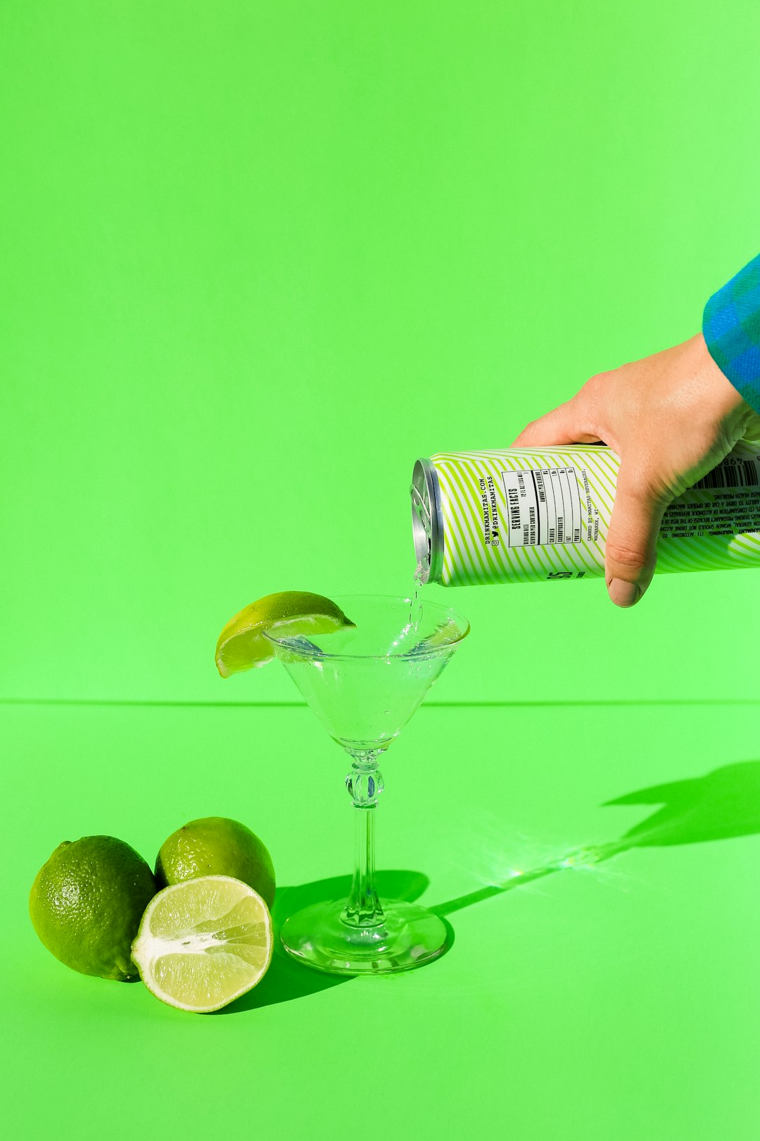 person holding clear wine glass with green liquid