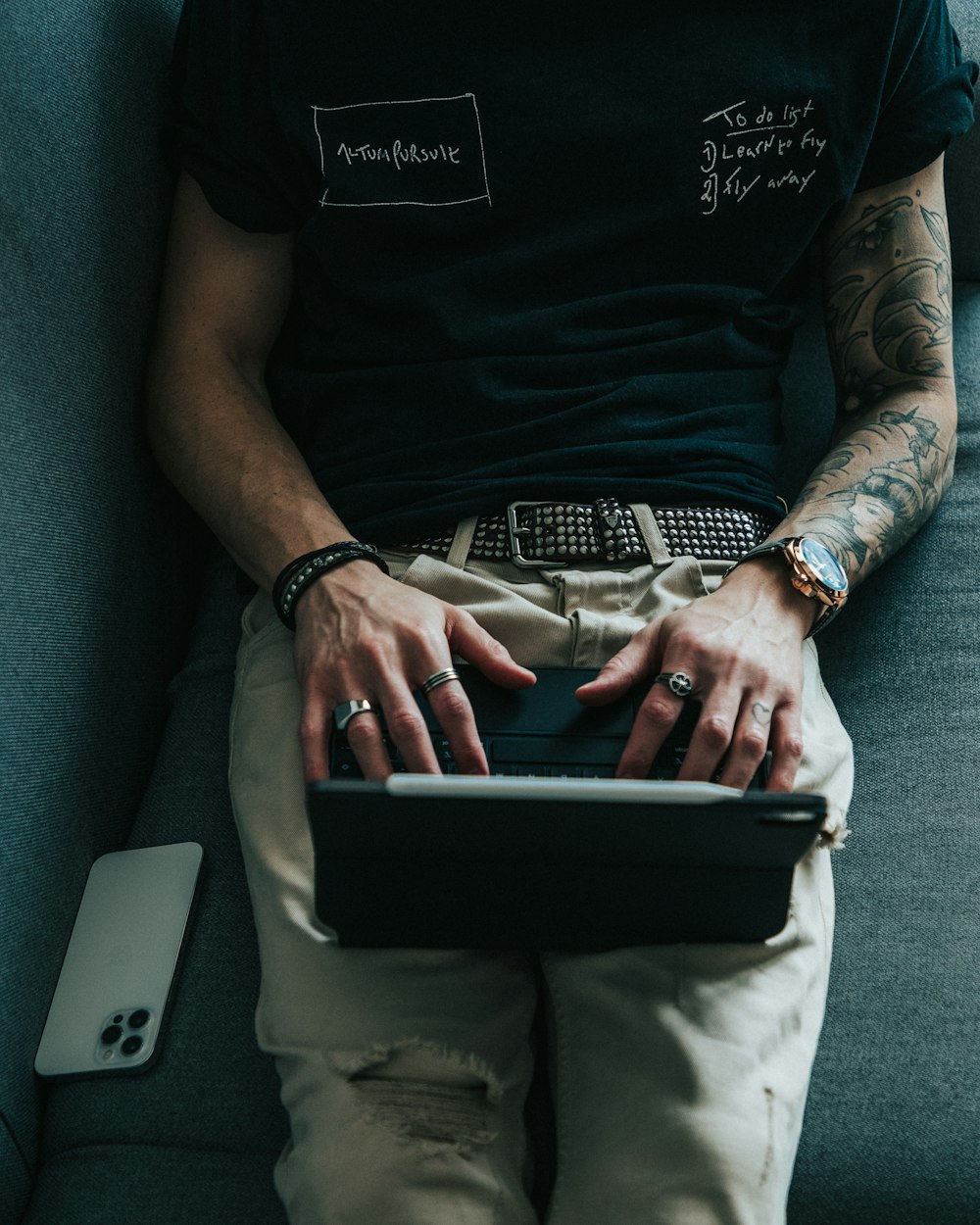 man in black t-shirt and gray pants holding black tablet computer