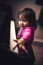 girl in pink long sleeve shirt playing piano