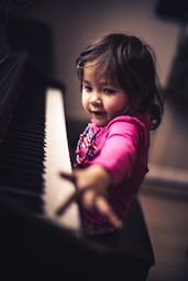 girl in pink long sleeve shirt playing piano