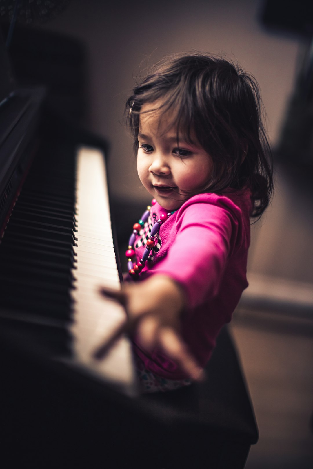 girl in pink long sleeve shirt playing piano