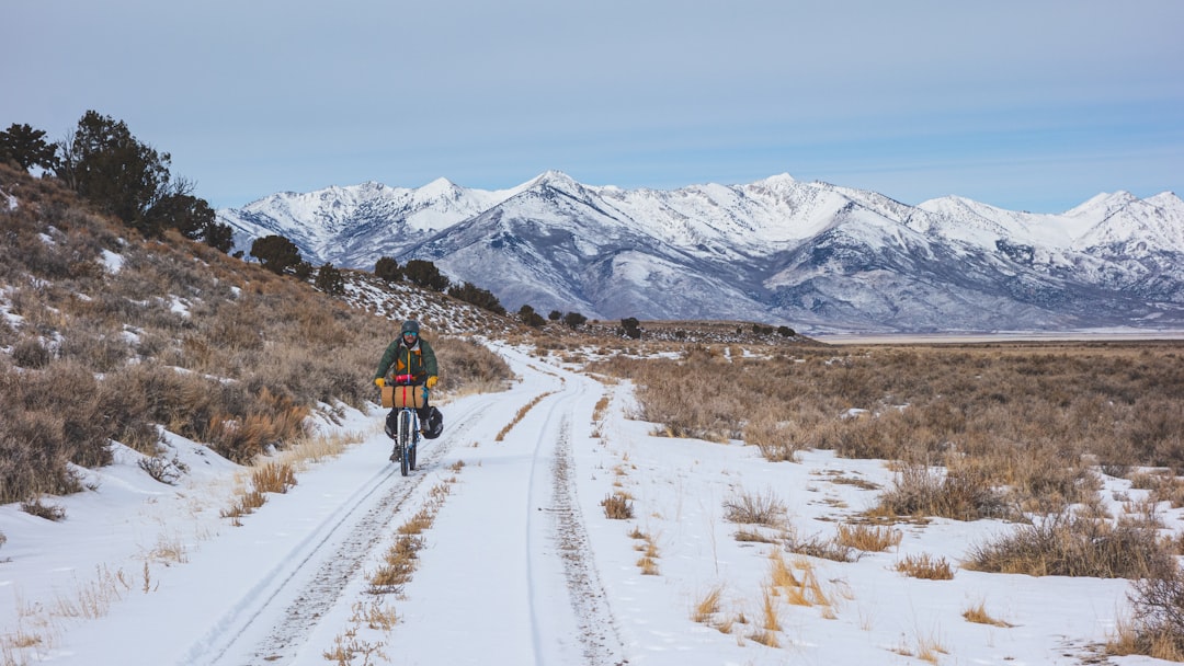 man riding bicycle on snow covered mountain during daytime