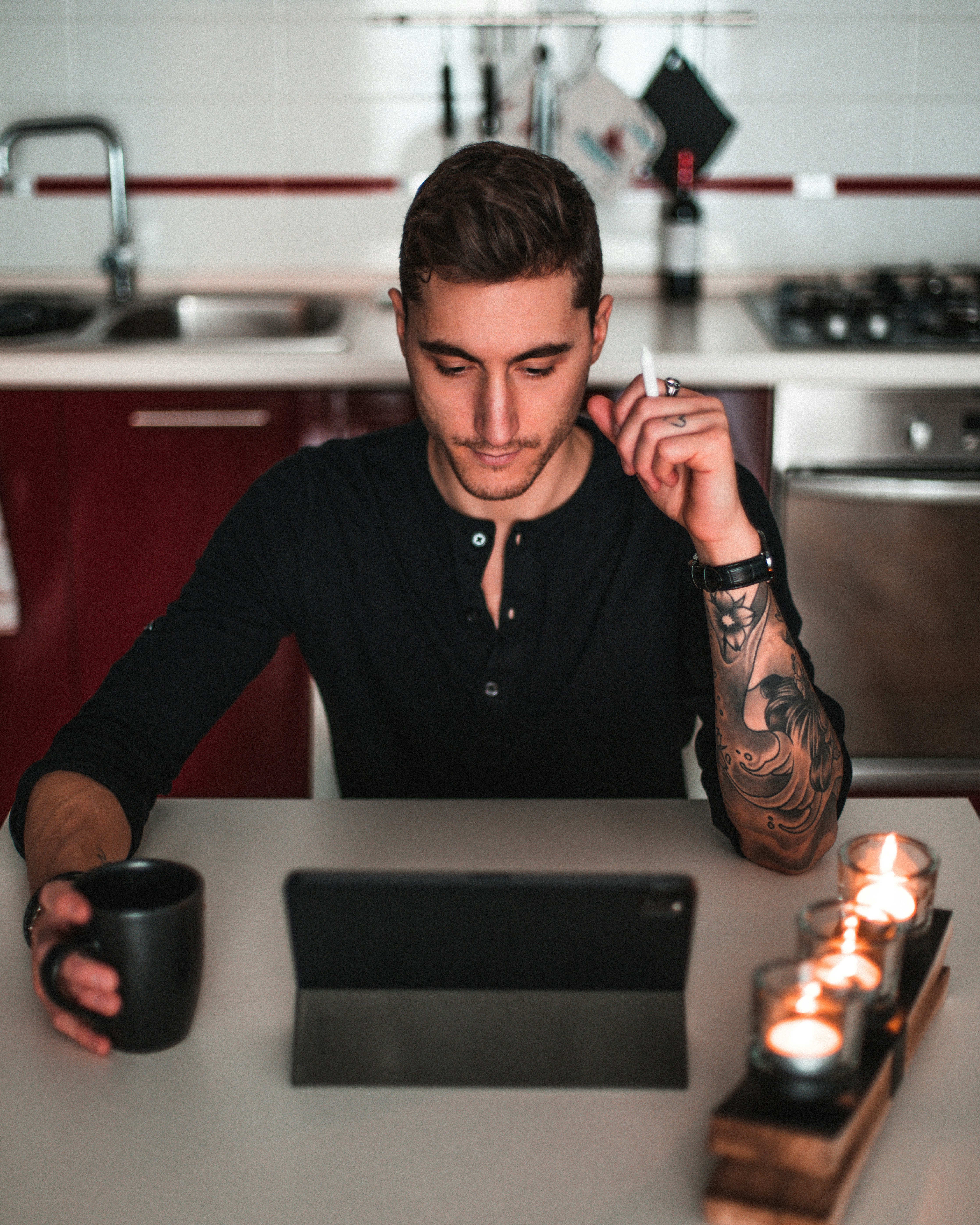 Mann in schwarz-rotem Langarmshirt mit rotem Keramikbecher