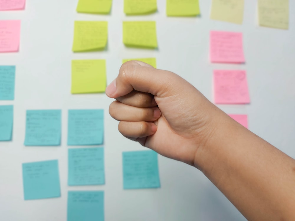 person holding yellow and pink sticky notes