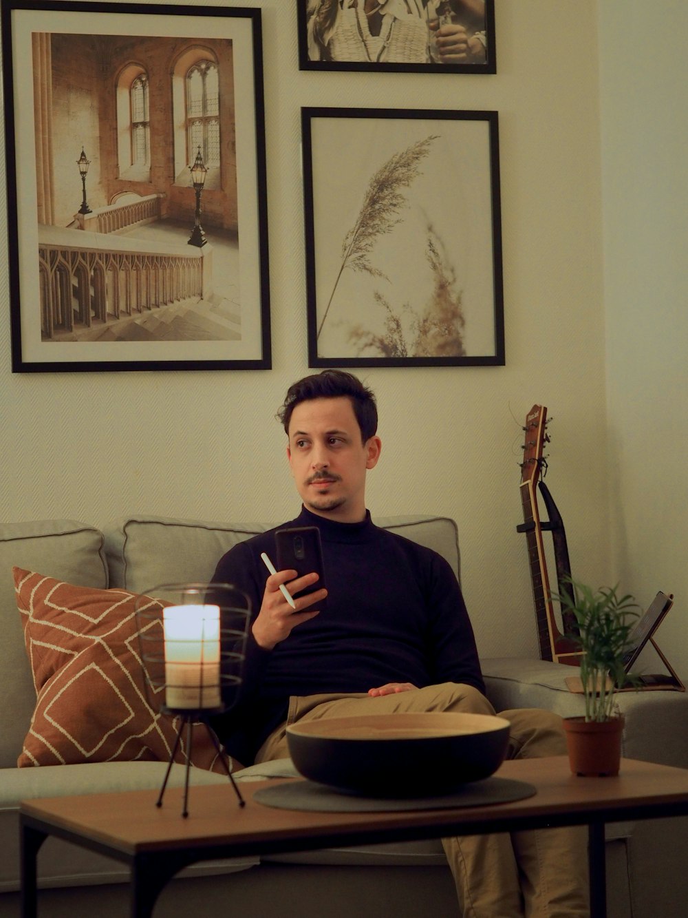 man in black long sleeve shirt sitting on brown and white sofa