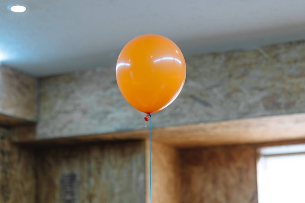orangefarbener Ballon an weißer Wand