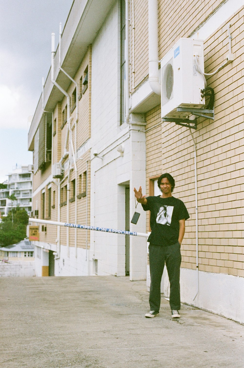 man in black t-shirt and black pants standing beside beige concrete building during daytime