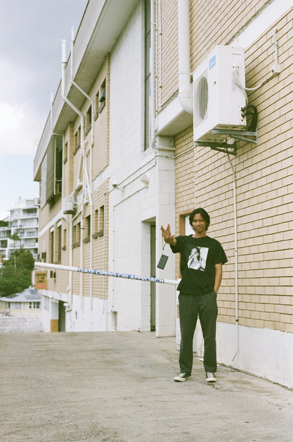 man in black t-shirt and black pants standing beside beige concrete building during daytime