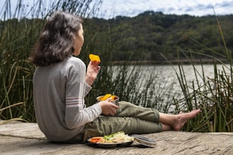 woman in gray long sleeve shirt sitting on brown wooden dock during daytime
