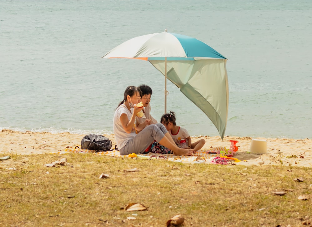 2 women sitting on beach sand during daytime