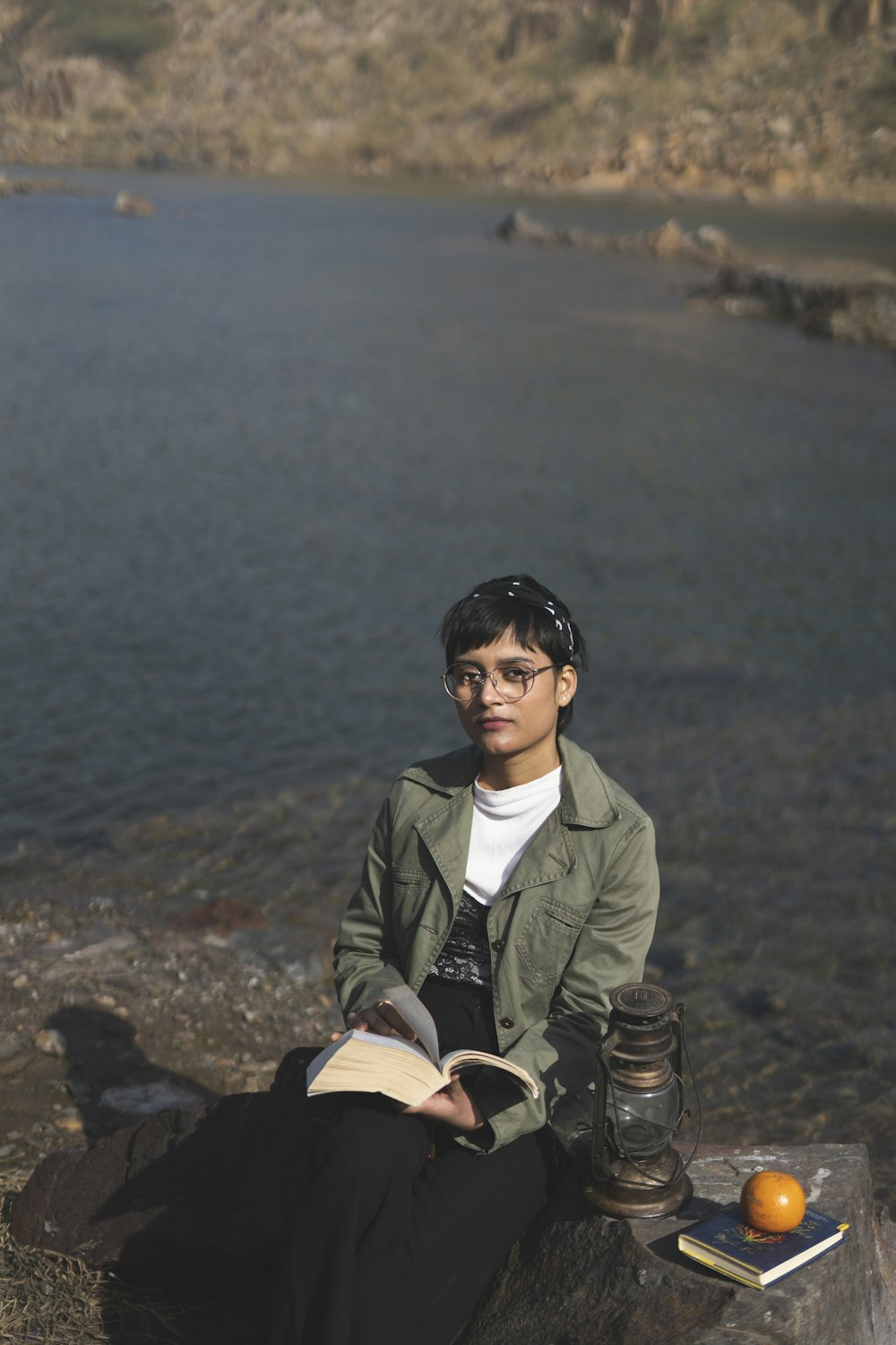 woman in green coat sitting on rock