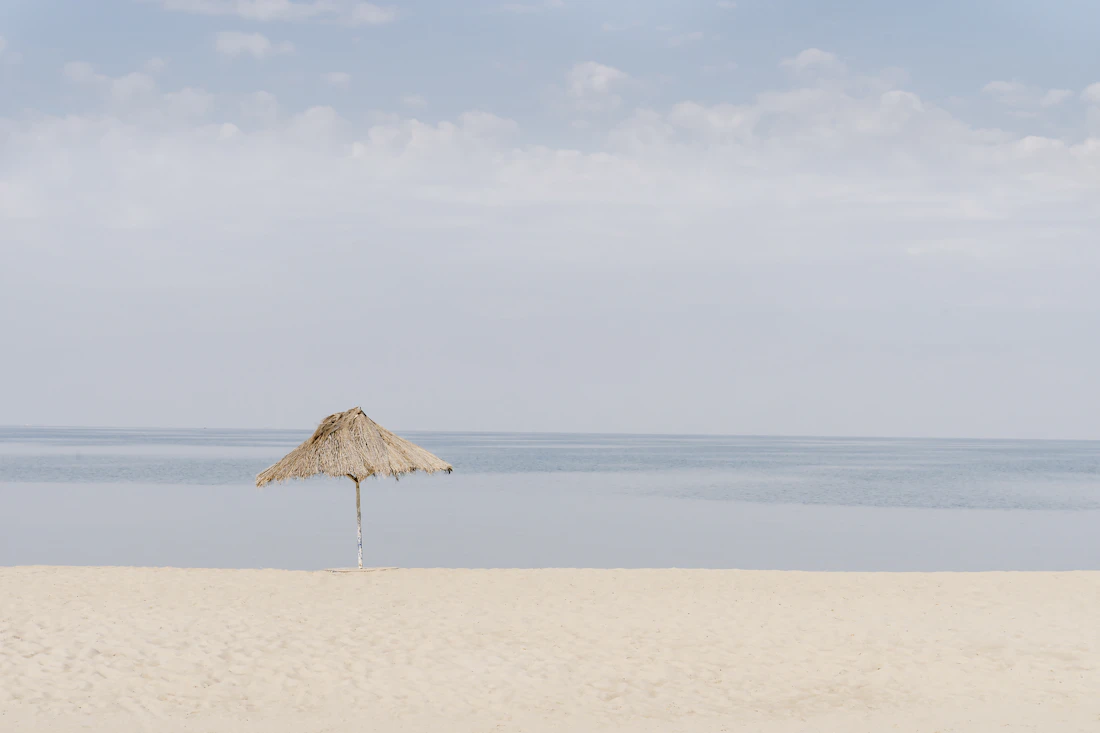 A lone thatched umbrella on the quiet white-sand shore of Lake Tanganyika, Burundi