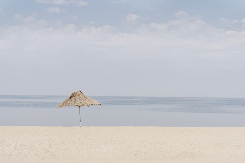 brown beach umbrella on white sand during daytime
