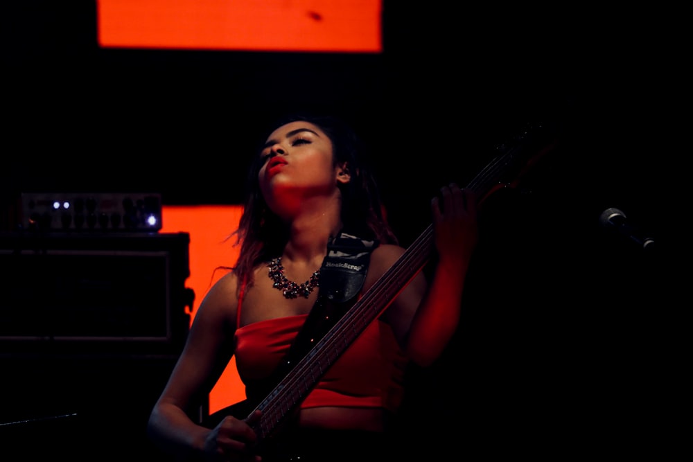 woman in black tank top holding guitar