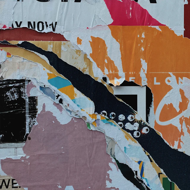 Layers of torn colorful paper posters with fragments of text and graphic patterns