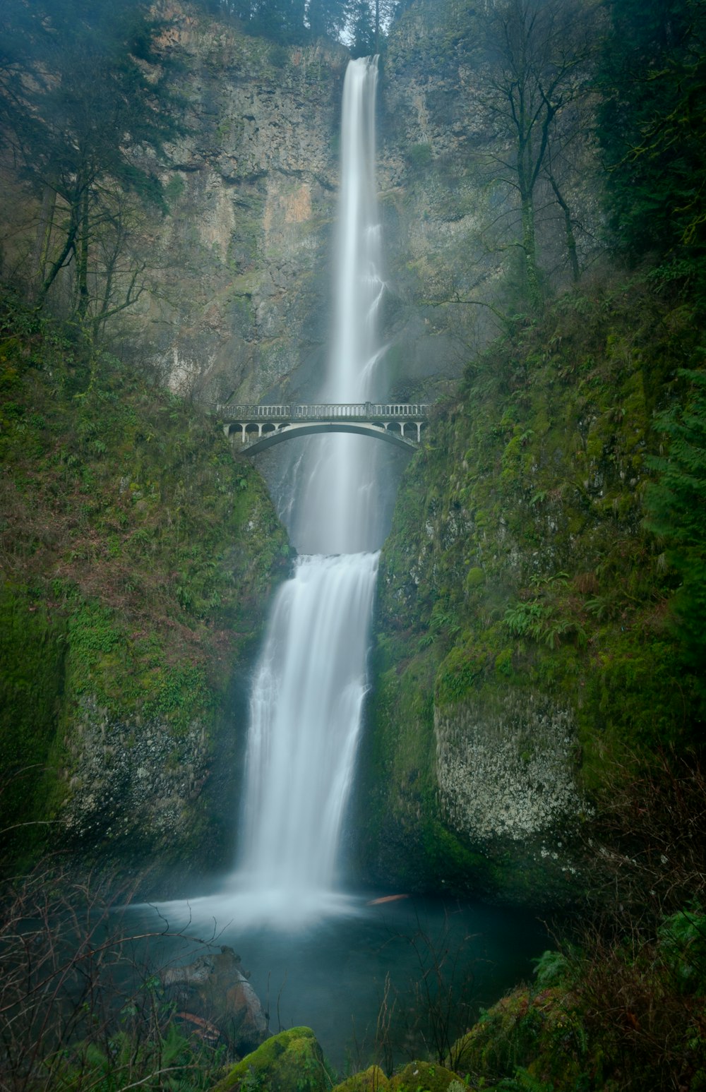 white bridge over waterfalls during daytime