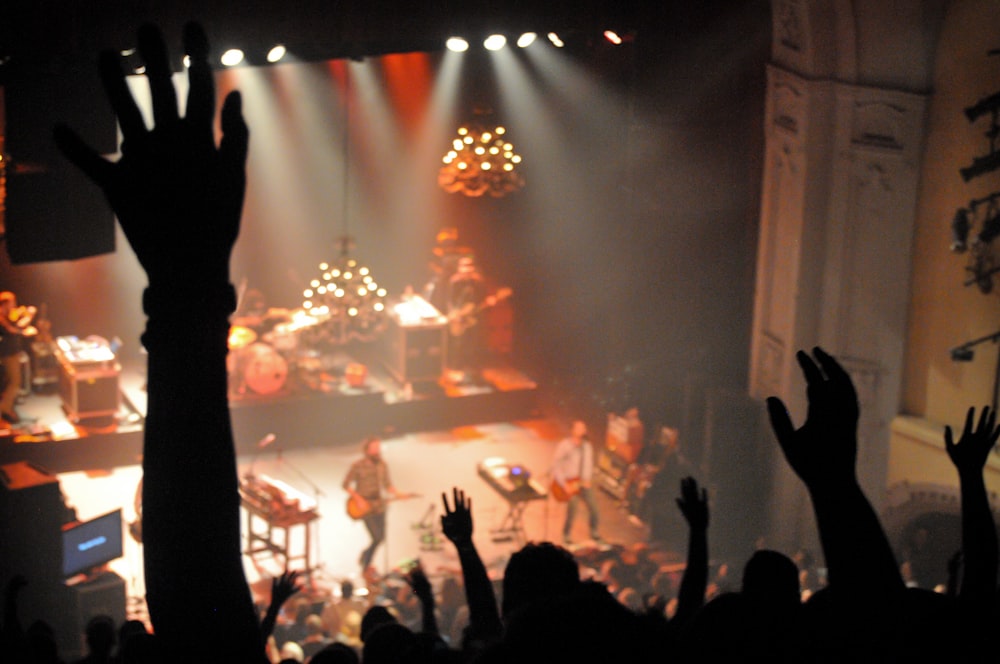 people standing on stage with lights turned on during nighttime