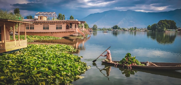 man in red shirt riding on brown boat on lake during daytime