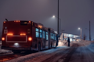red bus on snow covered road during night time