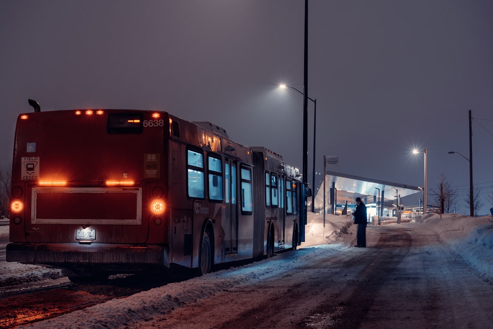 red bus on snow covered road during night time