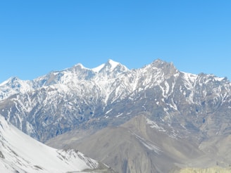 Snow-capped mountains and rugged terrain of Ladakh under a clear blue sky.