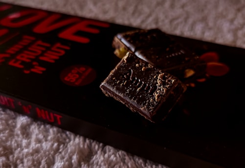 Close-up of a natural chocolate bar with nuts on a wooden table, highlighting its wholesome ingredients.