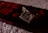 A close-up view of a chocolate bar with nuts, placed on its packaging. The chocolate appears rich and dark with visible nut pieces, and the packaging displays bold red text indicating 'fruit 'n' nut' and '55% cocoa'. The background is a soft, textured surface.