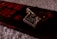 A close-up view of a chocolate bar with nuts, placed on its packaging. The chocolate appears rich and dark with visible nut pieces, and the packaging displays bold red text indicating 'fruit 'n' nut' and '55% cocoa'. The background is a soft, textured surface.