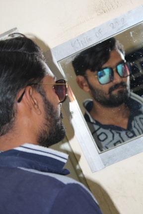 Man admiring his reflection wearing contemporary obsidian black glasses in ambient lighting.