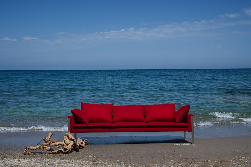 rote gepolsterte Couch am Strandufer tagsüber