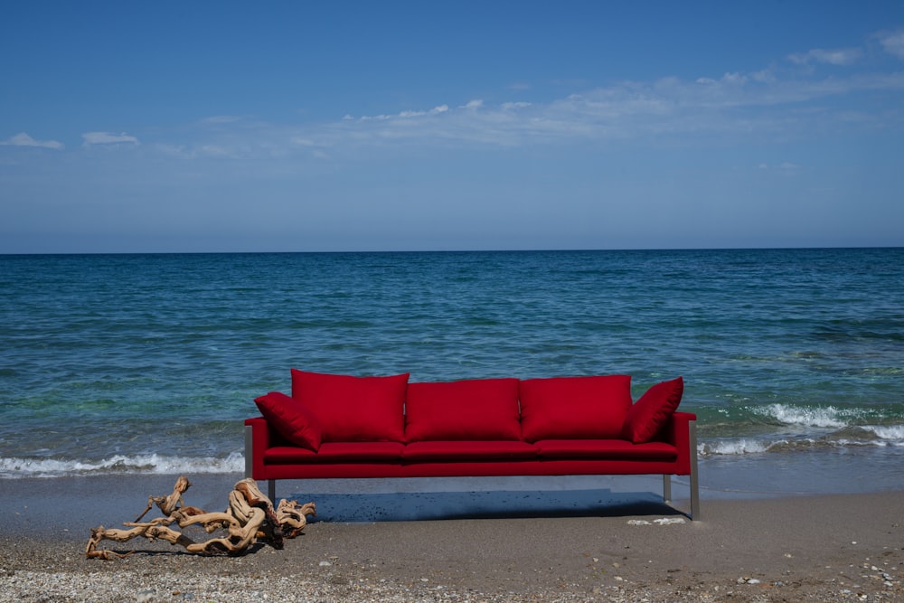 canapé rembourré rouge sur le rivage de la plage pendant la journée