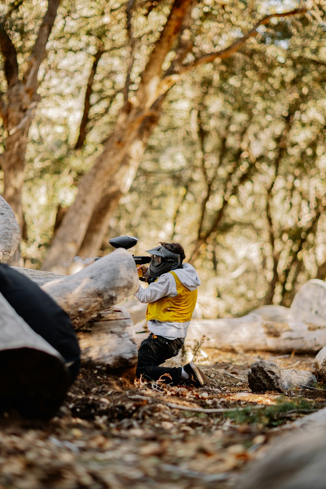 man in yellow jacket and black pants carrying backpack standing on brown dried leaves during daytime