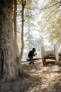 man in black jacket sitting on brown wooden bench near brown trees during daytime