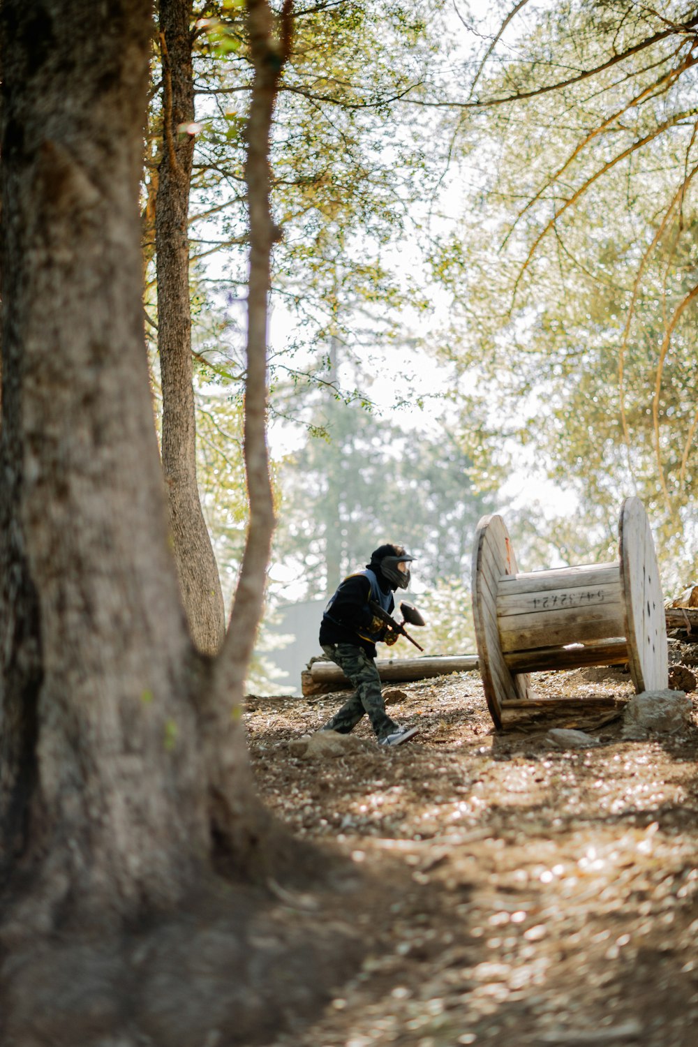 homme en veste noire assis sur un banc en bois brun près d’arbres bruns pendant la journée